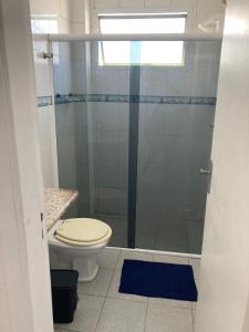 a bathroom with a toilet and a glass shower at Apto aconchegante pertinho da praia in Guarujá