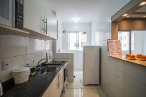 eine weiße Küche mit Spüle und Kühlschrank in der Unterkunft Acomodações Campinas By Rental in São José