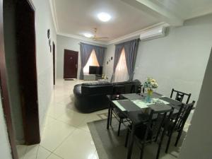 a living room with a table and a black couch at Jessica's Villa in Accra