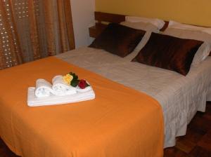Una cama con toallas y flores encima. en Sao Roque en Portimão