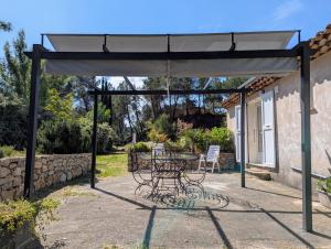a patio with a table and chairs under a canopy at Gîte La Clef du Sud - Cosy 4 pers, parking gratuit, EuroVelo 8 in Salernes