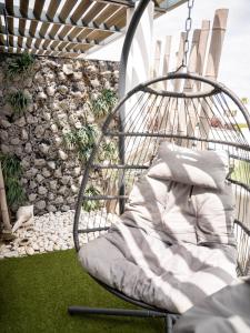a swinging chair on a patio with a rock wall at Appartement de L'Espiguette in Le Grau-du-Roi