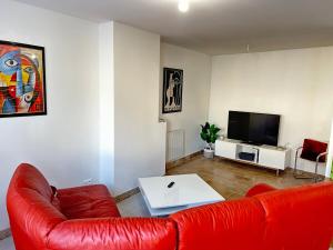 a living room with a red couch and a tv at Le P'ti Mignat - Jolie maison avec terrasse in Suèvres