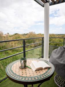 a table with a book and a coffee cup on a balcony at Appartement de L'Espiguette in Le Grau-du-Roi
