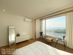 a bedroom with a bed and a large window at Gongzone Stay in Jeju
