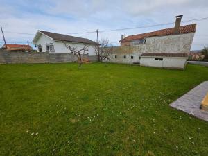 ein grüner Hof mit einem Haus und einem Gebäude in der Unterkunft Casa Angelín Muros del Nalón 4 Hab, 2 baños 1 aseo - VV-3049-AS in Muros de Nalón