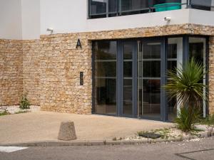 a building with large glass doors on the side of it at Appartement de L'Espiguette in Le Grau-du-Roi
