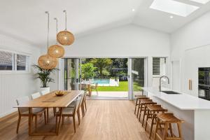 eine Küche und ein Esszimmer mit einem Holztisch und Stühlen in der Unterkunft Cove Beach House by Coast Hosting in Umina Beach 