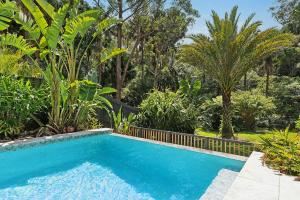 ein Swimmingpool in einem Garten mit Bäumen in der Unterkunft Cove Beach House by Coast Hosting in Umina Beach 
