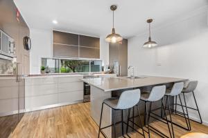 a kitchen with white cabinets and a island with bar stools at Lake Vista 2 0 By Coast Hosting in Budgewoi