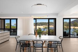 a kitchen and dining room with a white table and chairs at Maggie's by Coast Hosting in North Avoca