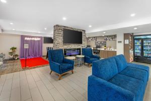a waiting room with blue chairs and a tv at MainStay Suites Oakbrook Terrace - Chicago in Oakbrook Terrace