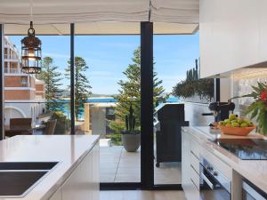 een keuken met witte werkbladen en een groot raam bij PineTree Penthouse by Coast Hosting in Terrigal