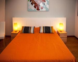 a bedroom with an orange bed with two lamps at Casa Corinna in Ponsacco