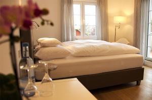 a bed with white sheets and pillows in a room at Landhotel Adler in Sigmarszell