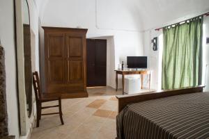 a bedroom with a bed and a chair and a television at 100 Craste in Ugento
