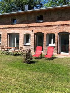 two red chairs sitting in front of a brick building at Ferienwohnung Alte Schmiede mit Gutspark in Rambin