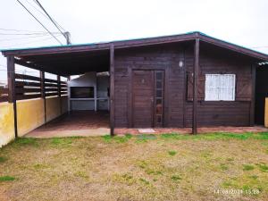 a small wooden building with a door in a yard at Las Mozitas II in Chuy