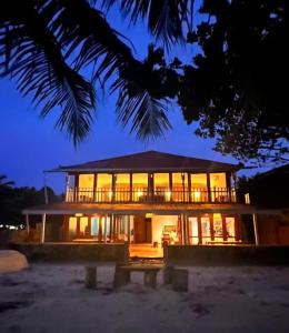 a large building with a large deck at night at Twin Palms Villa and Homestay in Tuapejat