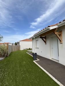 a white house with a yard with green grass at Maison Proche Centre Ville in Biscarrosse