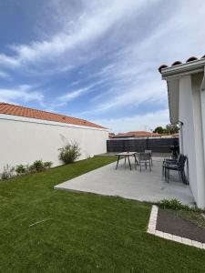 a patio with tables and chairs in a yard at Maison Proche Centre Ville in Biscarrosse