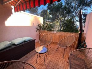 a patio with three chairs and a bed and a fence at Confort et évasion à l'Almanarre in Hyères