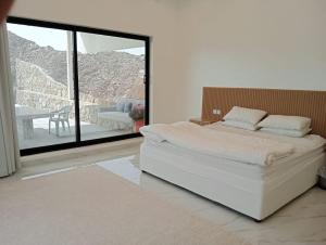 a bedroom with a large white bed and a balcony at Hatta Guest house Resort in Būbādī +34 photos