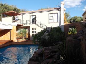 a house with a swimming pool in front of a house at Homestay Travel Guest House in Roodepoort