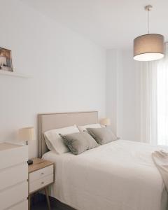 a white bedroom with a white bed and a desk at Marina Real I - Casa Areca in Denia