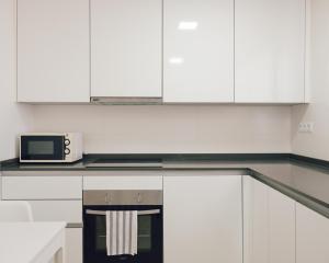 a kitchen with white cabinets and a microwave at Marina Real I - Casa Areca in Denia