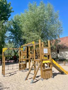 a wooden playground with a yellow slide at Camping Les Tourterelles in Rang-du-Fliers