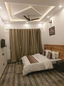 a bedroom with a large bed with a ceiling fan at Nature Oaks Luxury stayz Nainital in Bhīm Tāl