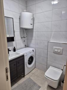 a bathroom with a washing machine and a sink at Apartments 402 in Bar