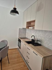 a kitchen with white cabinets and a sink and a table at Apartments 402 in Bar +3 photos