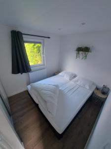 a bedroom with a white bed with a window at Fiets & Relax Chalet in Den Bommel
