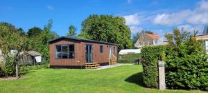 a tiny house in a yard with a house at Fiets & Relax Chalet in Den Bommel