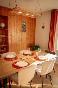 a dining room table with white plates and glasses on it at L'Edelweiss - Au pied des montagnes in La Lechere +16 photos