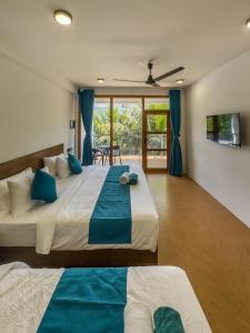 two beds in a room with blue curtains at The Palms Thoddoo in Thoddoo