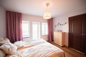 a bedroom with a bed and a dresser and windows at Angelica Apartment in Vilnius
