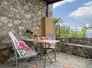 a table and chairs on a patio with a stone wall at Lina's Art and Stone Studio in Verga Kalamata