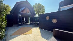 a house with a black roof and a patio at 't Boschhuys by Droomvilla in Bergen
