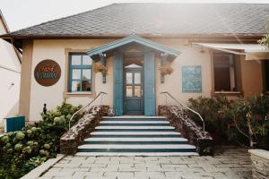a house with a blue door and stairs at Fészek -Étel és Hotel-Zánka in Zánka