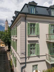 a white building with green shutters on it at Steinach Townhouse Meran in Merano