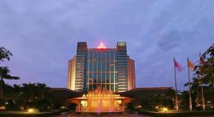 a tall building with a fountain in front of it at Gladden Hotel Shilong in Dongguan