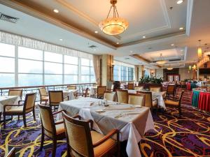 a dining room with tables and chairs and windows at Gladden Hotel Shilong in Dongguan