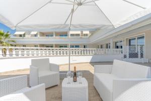 een witte patio met witte stoelen en een parasol bij Casa Royale al Relais Du Lac in Desenzano del Garda