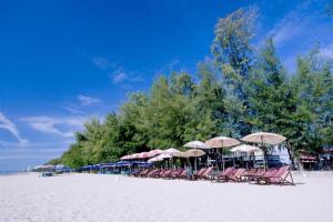a group of chairs and umbrellas on a beach at Baan Taklom Chomtalay in Ban Sahakham