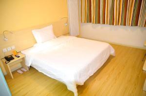 a bedroom with a white bed and a wooden floor at 7 Days Inn Shijiazhuang Zhengding Airport in Xinle +4 photos
