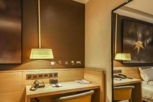 une chambre d'hôtel avec un bureau et un lit dans l'établissement IU Hotel Zhengzhou Wenhua Road Sanquan Road Branch, à Zhengzhou