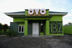 a green building with a large ovo sign on it at Hotel O Abz Guest House Syariah in Jambi